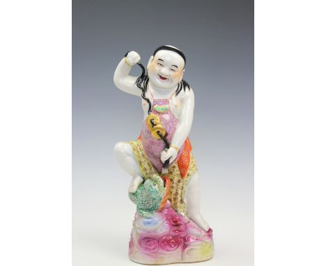 A Chinese figural model depicting Gama Sennin, designed as a standing figure holding a cash string with three legged toad to 