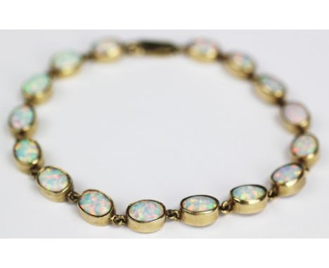 An opal set bracelet, the sixteen oval synthetic opals each within yellow metal collet setting with clasp stamped '375', 21cm