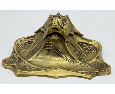 An Art Nouveau brass inkwell with stylised fish lid, with ceramic ink well, 21cm wide, 9cm high, 14cm deep.