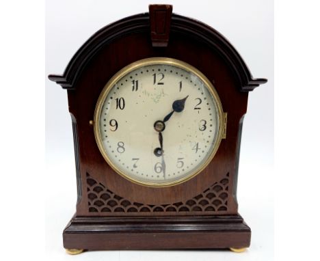 An Edwardian mahogany cased mantle clock with fretwork decoration on brass bun feet. 