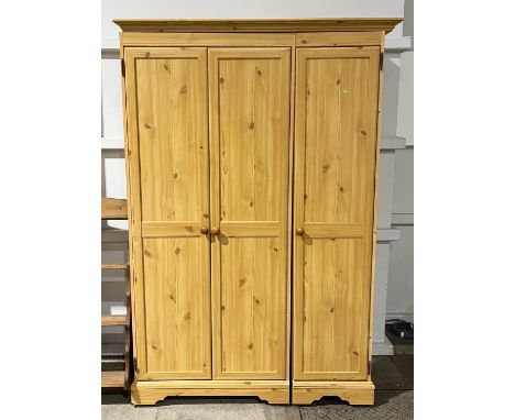 A pine effect triple wardrobe in two sections, each with wheeled base - W127cm x H189cm x D50cm