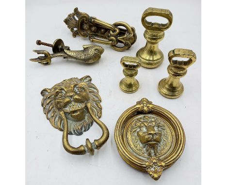 A collection of vintage brass door knockers and a set of three brass graduated weights.
