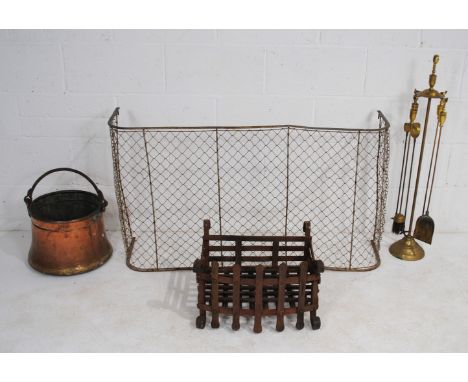 A copper fire bucket, along with a brass fireside companion set, a brass wirework fire curb and a cast iron fire grate