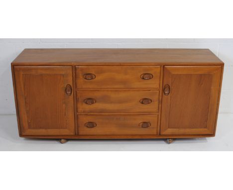An Ercol elm sideboard, with three drawers surmounted by cupboards, raised on castors - length 155.5cm, depth 45cm, height 68