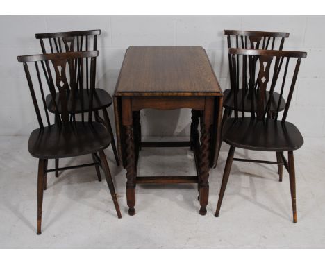 An Ercol style set of four stick-back dining chairs, along with an antique oak drop-leaf table, with barley twist supports