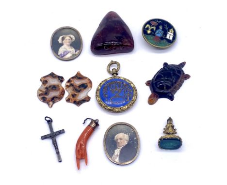 An antique branch coral charm in the form of a hand, a piece of amber, a mourning locket and a foil backed seal etched with "