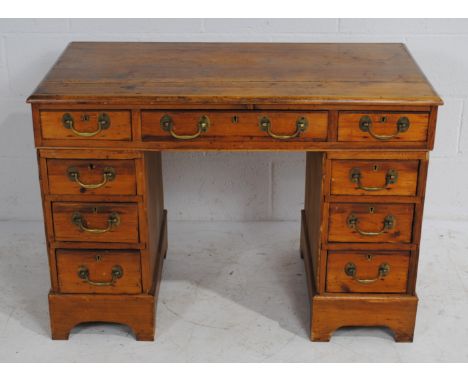 An antique rustic pine kneehole desk, with nine drawers, raised on bracket feet - length 104.5cm, depth 57cm, height 73cm