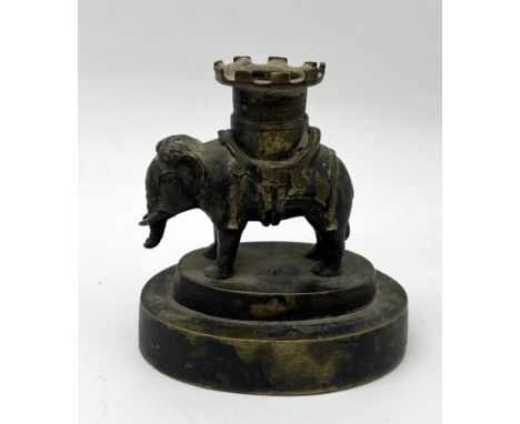 An antique bronze candlestick in the form of an elephant with castellated top - height 10cm
