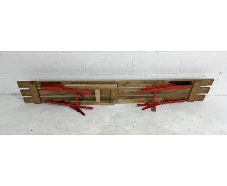 A folding wooden bench on metal legs with central folding support