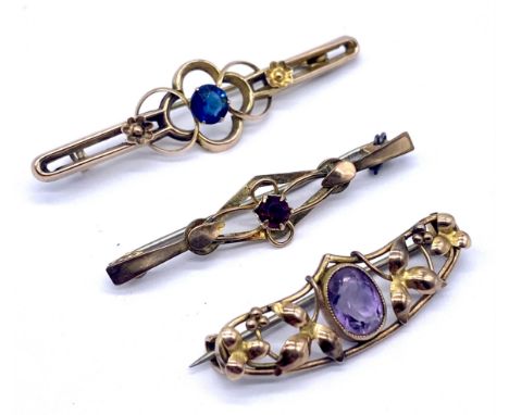 A 9ct gold bar brooch set with garnet, another set with blue zircon and an amethyst set bar brooch tests as 9ct, 5.2g total w