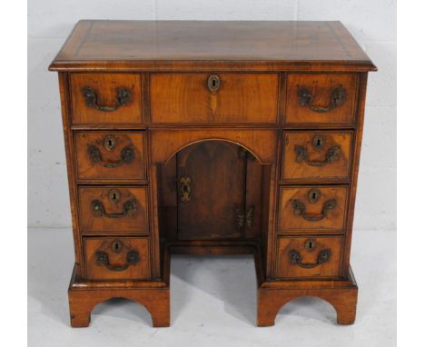 A Queen Anne inlaid walnut kneehole desk, with seven drawers and central cupboard under, raised on bracket feet - with key - 