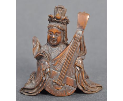 A fine Japanese believed Edo period / 19th century carved wooden signed netsuke. The netsuke in the form of a deity playing a