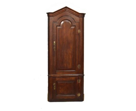 George III oak two section standing corner cupboard, the upper section fitted arch shaped fielded panel door with crossbanded