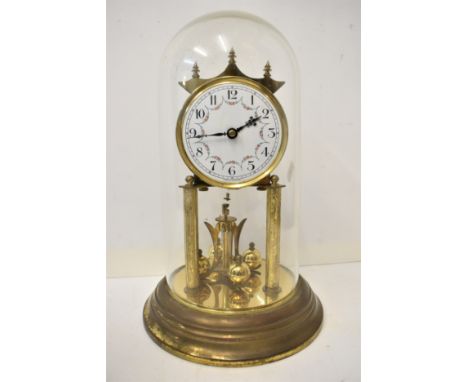 An early 20th century anniversary clock with glass dome, white enamel dial having Arabic numerals with floral swags, supporte