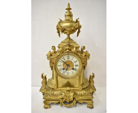 A 19th century French gilt metal mantel clock, the case having an urn shaped finial with floral swags, Grecian masks to the s