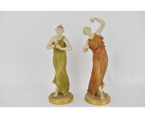 Two Royal Worcester Hadley figures each of a classical maidens one playing pipes, the other maracas, with long flowing dresse