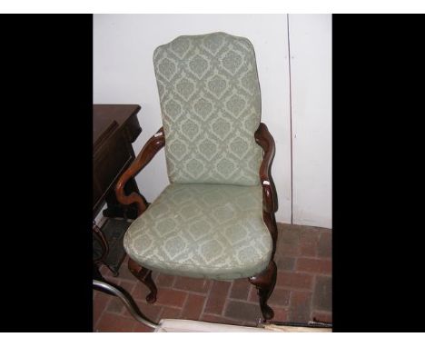 An armchair with cabriole front supports upholstered in light green floral material 