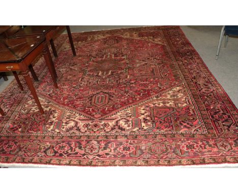 A Heriz carpet, the strawberry field of angular vines centred by cruciform medallion, framed by spandrel and samovar borders,