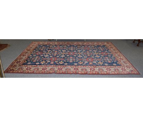 An Afghan carpet of Caucasian design, the abrash indigo field of stylised flower heads enclosed by ivory borders, 345cm by 24