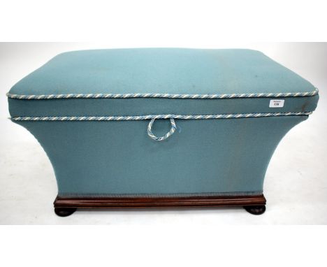 A BLUE UPHOLSTERED OTTOMAN STOOL of sarcophagus form and standing on turned feet 82cm long 