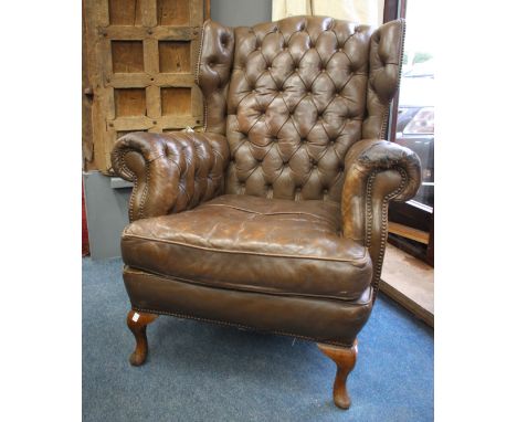 A BROWN LEATHER BUTTON UPHOLSTERED WING BACK ARMCHAIR, standing on short cabriole legs, approximately 95cm wide 