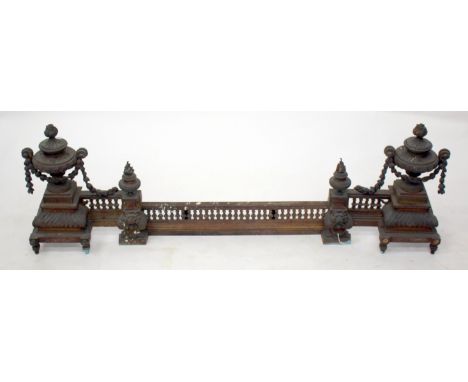 A 19TH CENTURY GILT BRASS FENDER with turned finial ends with square stepped bases and having lions mask mounts and an adjust