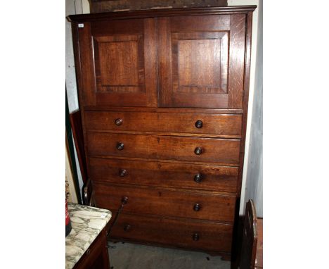 A 19TH CENTURY OAK LINEN PRESS with twin panelled cupboard doors over five graduated long drawers with turned knob handles an
