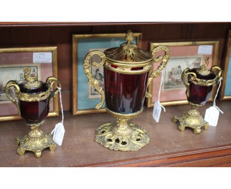 A GILT METAL MOUNTED RUBY GLASS POT POURRI GLASS, the pierced lid with pineapple knop and scrolling handles and on pierced sp