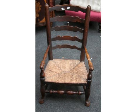 An early 19th century Lancashire ladder back nursing armchair, with rush seat over turned supports