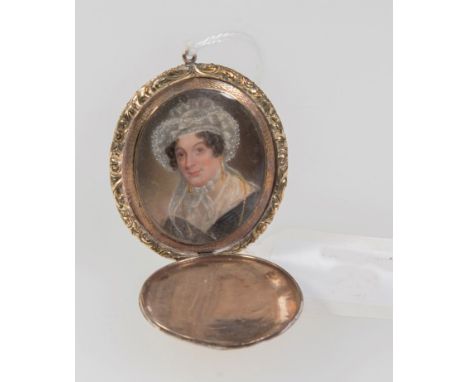 An early 19th century mourning locket, with hinged cover opening to reveal a head and shoulders portrait of a lady in lace bo