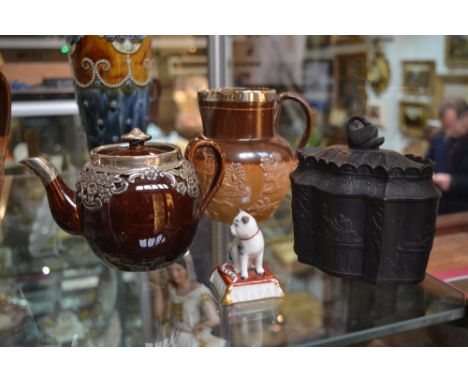 A Doulton silver mounted jug, a silver mounted teapot, a basalt tea caddy and a small Chelsea style model cat (4)