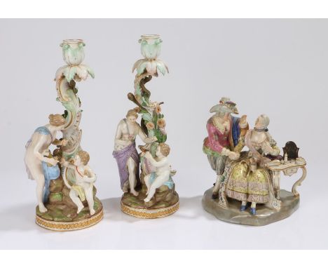 Pair of Meissen porcelain figural candlesticks, each with a scroll and swag tree trunk forming the candle stick and a female 