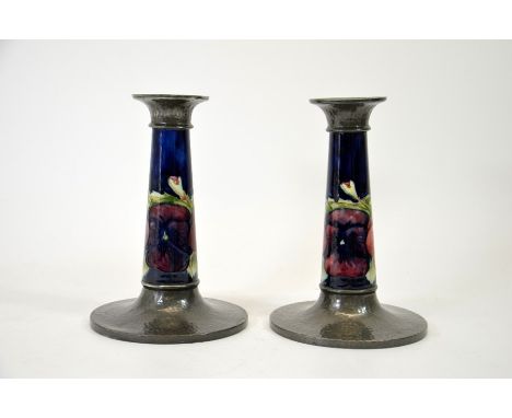 William Moorcroft for Liberty, a pair of Pansy, Tudric pewter mounted candlesticks, planished bases and sconces, 01362, 20cm 