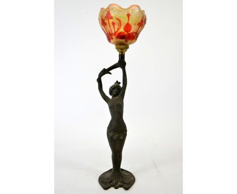 A French Art Nouveau bronzed figural table lamp, modelled as a woman, arms raised, holding a branch, supporting an iridescent