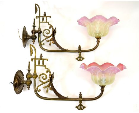 A pair of Aesthetic Movement brass wall lights, the angled arms with applied leaves and scroll brackets, turned geometric and