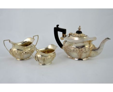 A Victorian silver three piece tea set, squat lobed ogee form with embossed foliate scroll decoration, ebony handle and finia