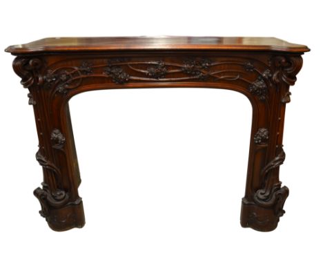 Louis Majorelle (attributed), a large Art Nouveau carved walnut fire surround, circa 1900, modelled in relief with flower hea