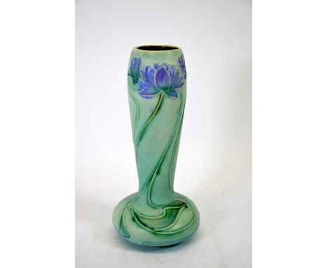 A Bretby Art Pottery vase, in the Art Nouveau style, tubelined with lilies and tendrils on an elongated globular body, impres