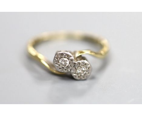 An 18ct &amp; plat, illusion set two stone diamond crossover ring, size K, gross 2.5 grams.