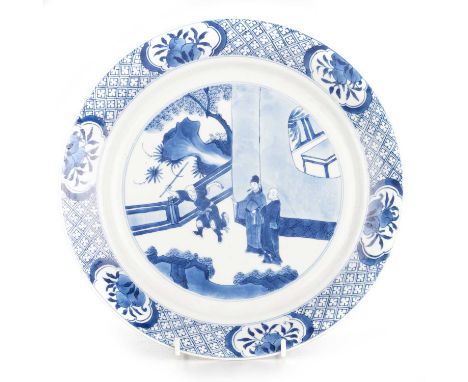 A CHINESE BLUE AND WHITE PORCELAIN DISH, KANGXI MARK AND PERIOD circular, underglaze blue painted with three figures in a gar