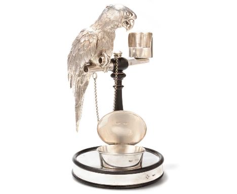 A VICTORIAN SILVER AND EBONISED WOOD NOVELTY INKWELL STAND by James Charles Edington, London 1862, modelled as a parrot sat u