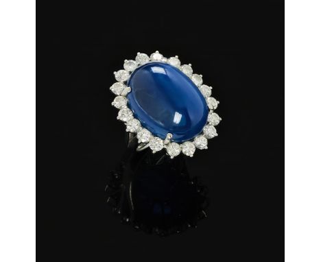 A DIAMOND AND CABOCHON NATURAL SAPPHIRE CLUSTER RING  The oval double cabochon sapphire weighing 42.50 carats in a four claw 