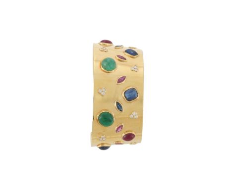 A MULTI GEM SET CUFF BANGLE  The tapering broad gold coloured bangle set with variously shaped cabochon and facetted sapphire