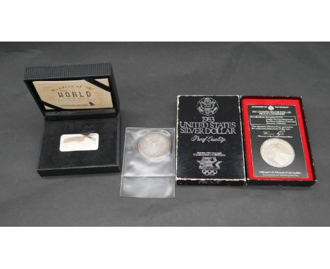 A cased Wonders of the World silver ingot with certificate, a 1983 Olympic US silver dollar proof coin in box and a 1879 US s