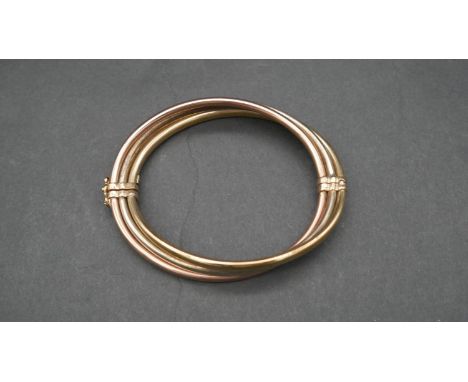 A hollow three colour twist 9ct gold bangle with clip and loop clasp. Hallmarked. D.8cm, 15.5g 