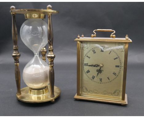 A vintage brass cased hourglass and a battery powered brass mantel clock with carrying handle. H.25cm 