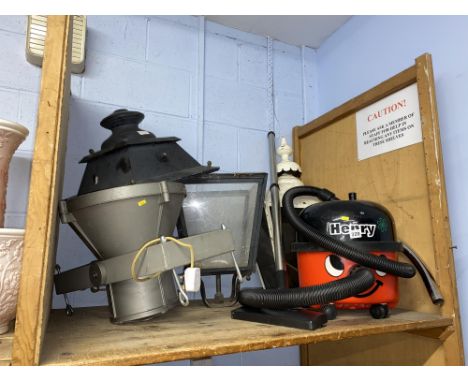 A shelf of outdoor lanterns, spot lamp and a Henry the Hoover vacuum cleaner