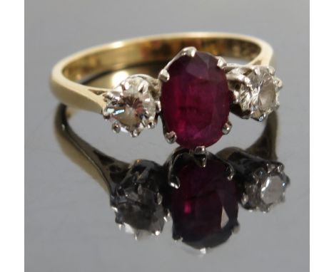 A ruby and diamond three stone ring, stamped '18ct', the oval cut approximately 7.2mmm x 5.4mm, flanked by brilliant cuts tot