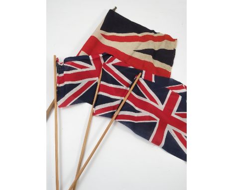 Sixteen vintage Union Jack flags, on wooden sticks, together with three larger Union Jack flags on wooden sticks and a Red En