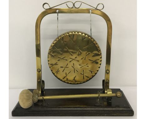A vintage freestanding brass gong, mounted on wooden plinth, with beater.  Approx. 29cm tall x 31cm wide.